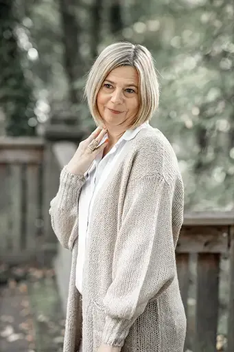 Natürliches Porträt einer Frau in heller Strickjacke vor einem grünen Hintergrund