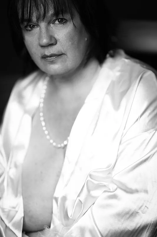 Schwarzweiß-Boudoir-Porträt einer Frau in einem hellen Satinmorgenmantel