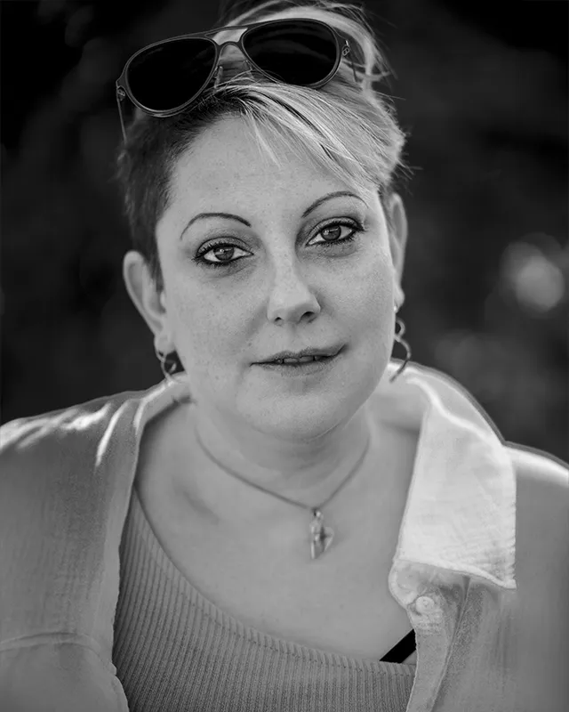 Schwarz-Weiß-Porträt einer Frau mit kurzem Haar und Sonnenbrille auf dem Kopf.